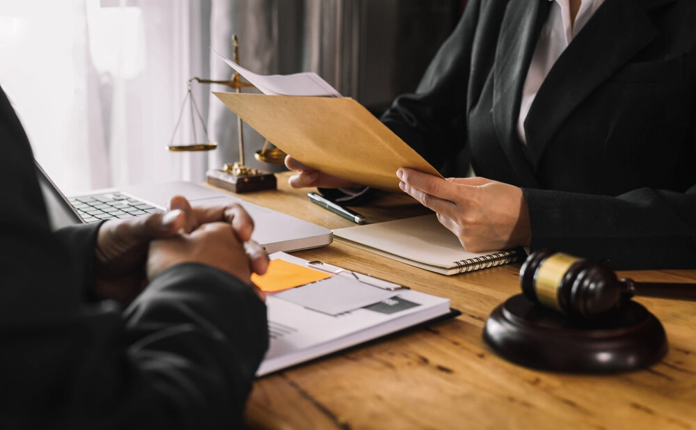 Business and lawyers discussing contract papers with brass scale on desk in office