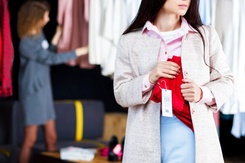 Closeup of young woman is stealing red jeans in store