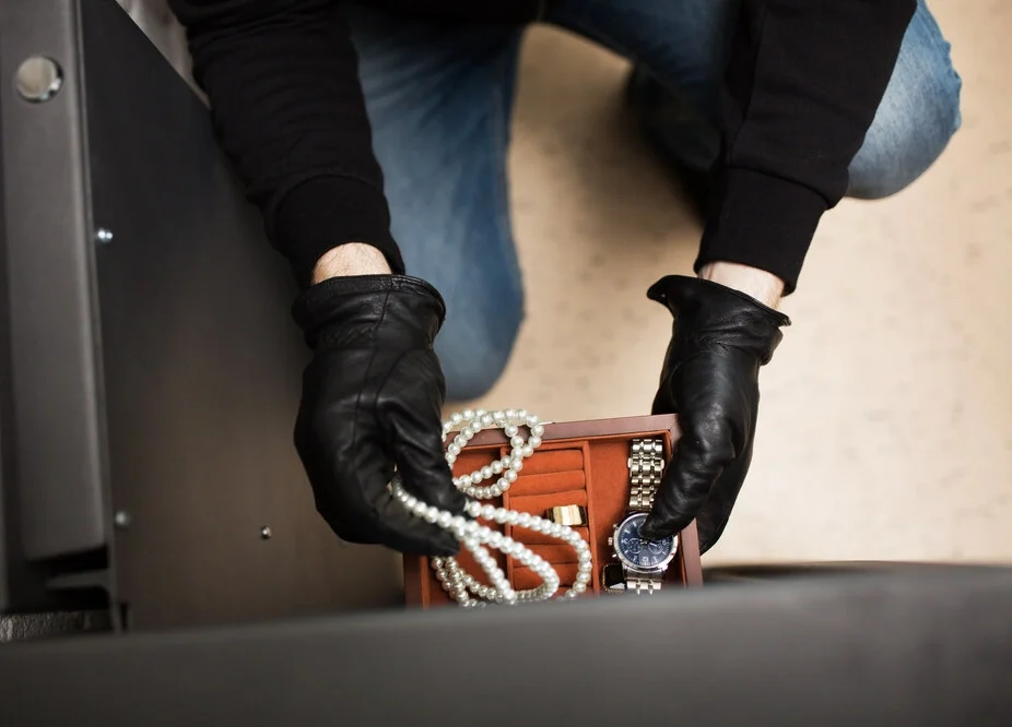 theft, burglary and people concept - thief stealing valuables from safe at crime scene