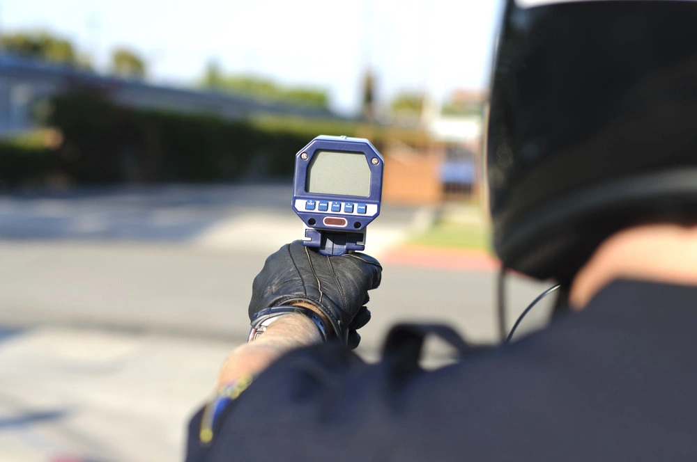 a motorcycle police officer aiming his radar gun a traffic.