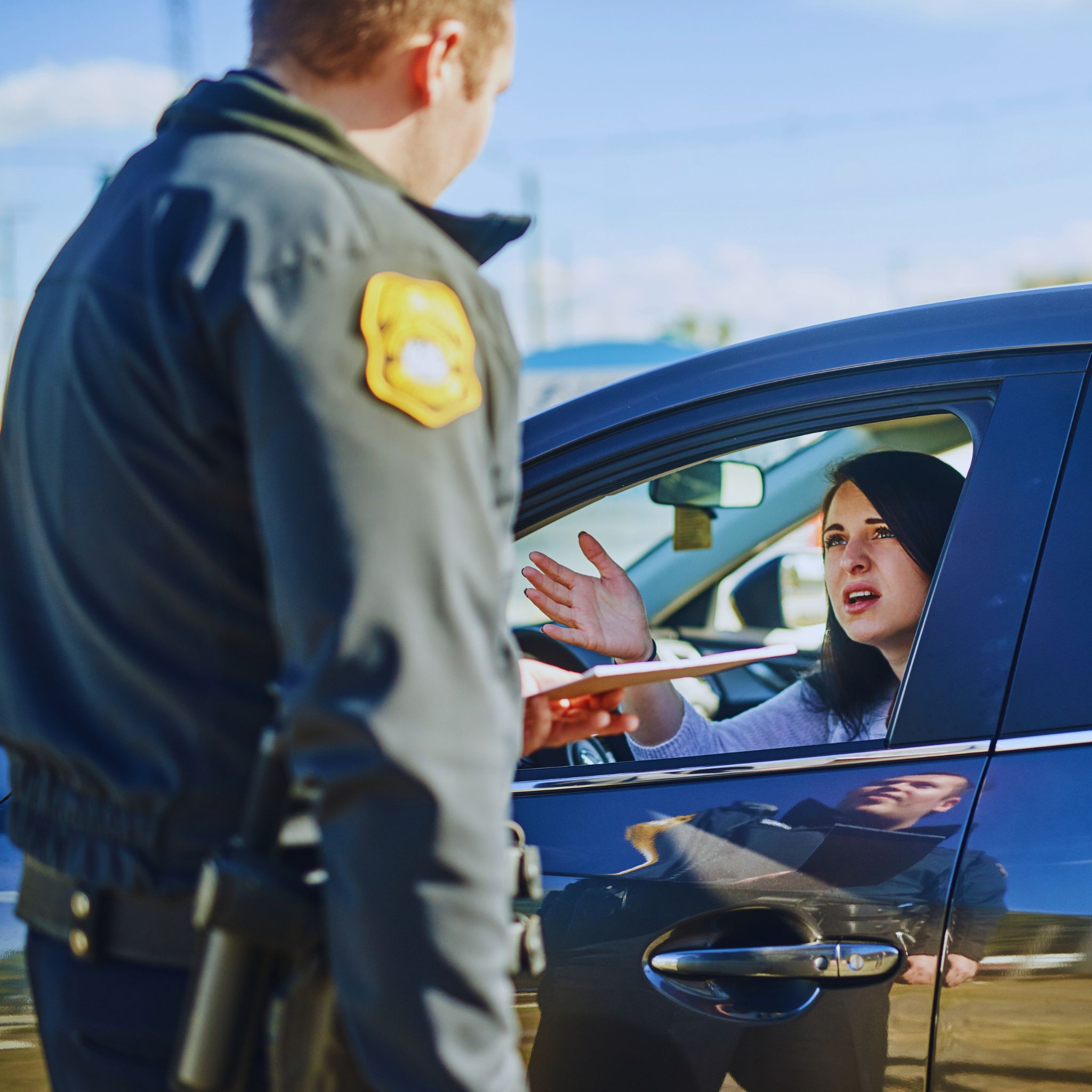 Worried driver receiving a traffic ticket from a police officer, emphasizing the need for a traffic ticket lawyer.