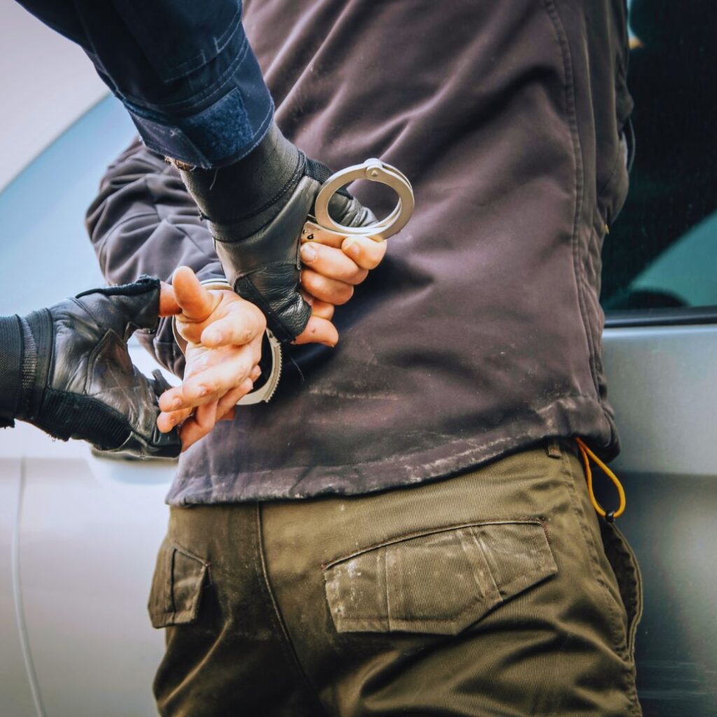 DUI causing injury: A driver being arrested by a police officer, highlighting the serious legal consequences of impaired driving.