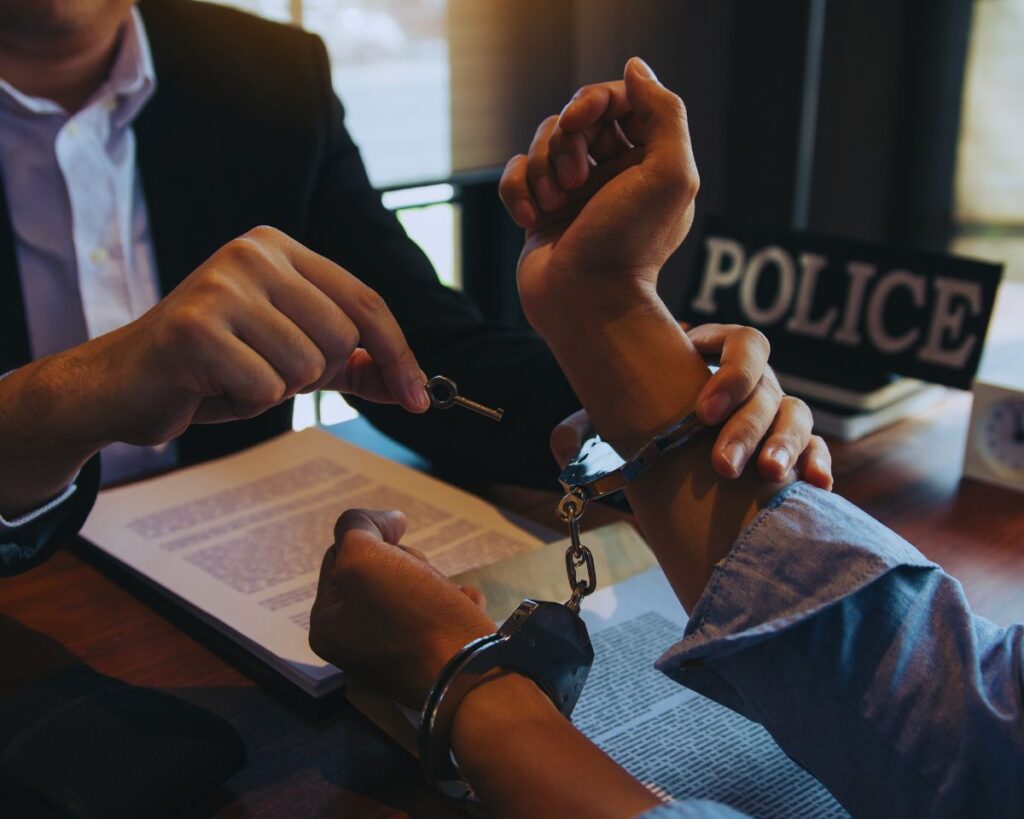 A driver in handcuffs being released after paying bail for a DUI charge, illustrating California DUI bail procedures.