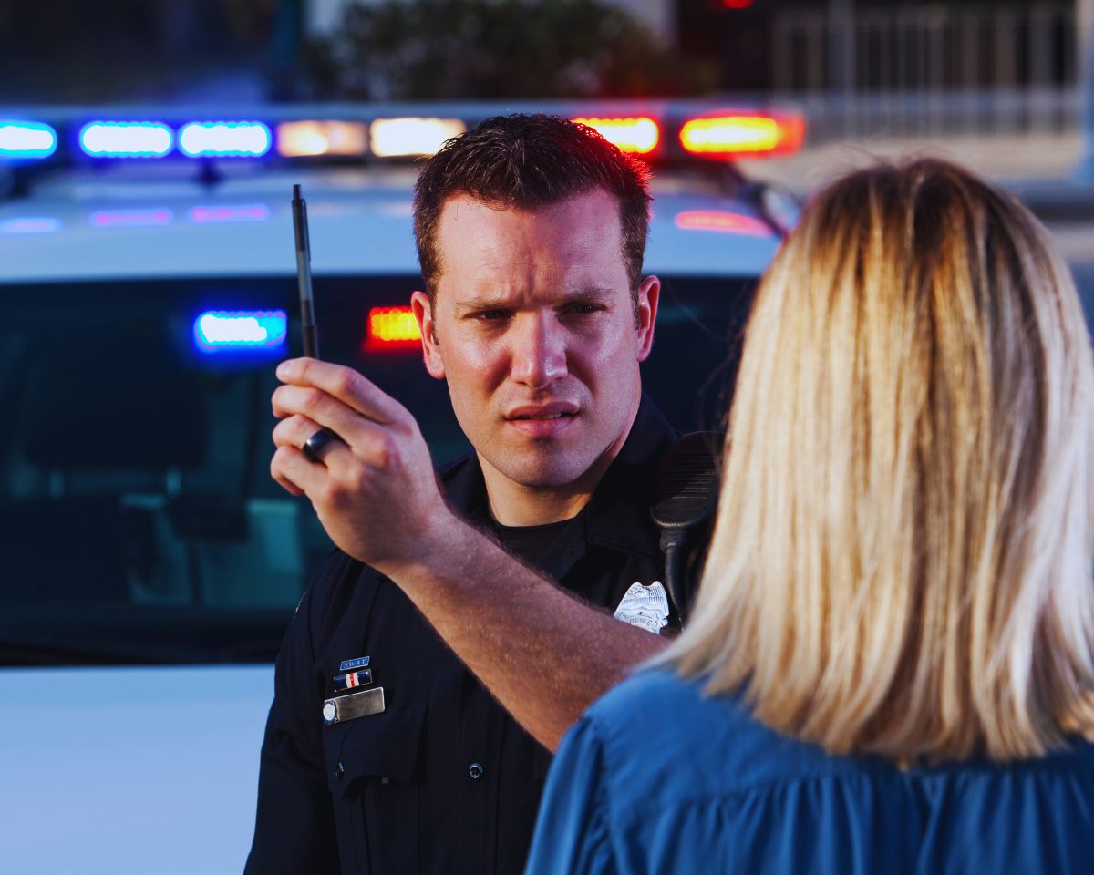 Law enforcement officer administering field sobriety tests to a driver during a DUI stop.