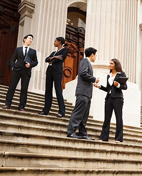 Four well dressed professionals in discussion on the exterior steps of a building