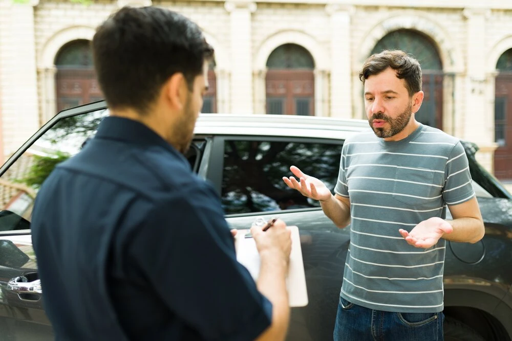 Stressed caucasian man arguing with a police officer writing a traffic speeding ticket