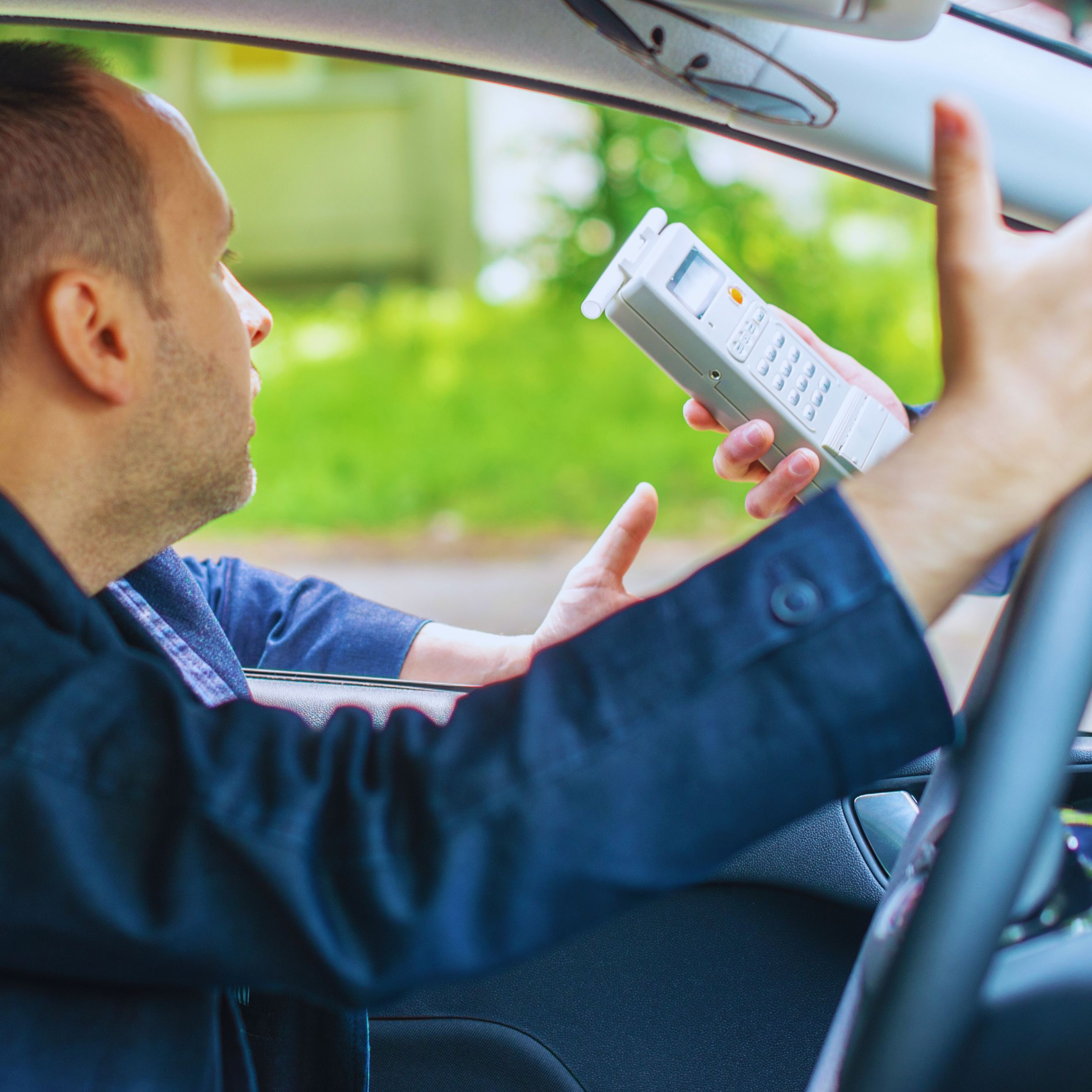 Refusing a Breathalyzer in California - Man inside a car refusing to take a breathalyzer test from a police officer,